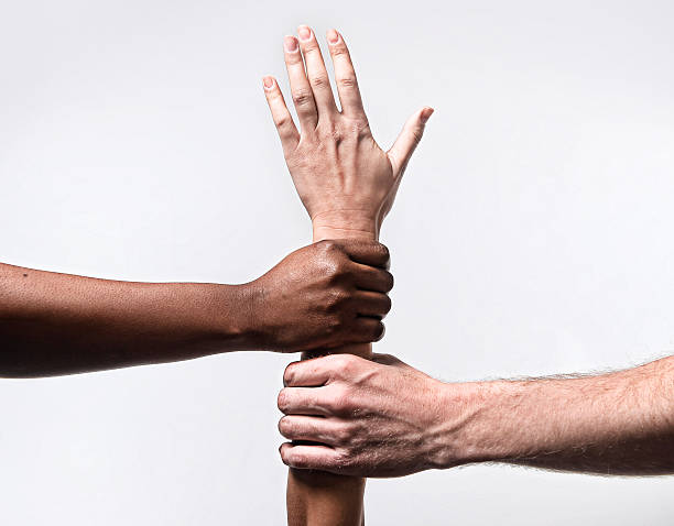 istock black African American hands holding Caucasian arm in world unity 465636092