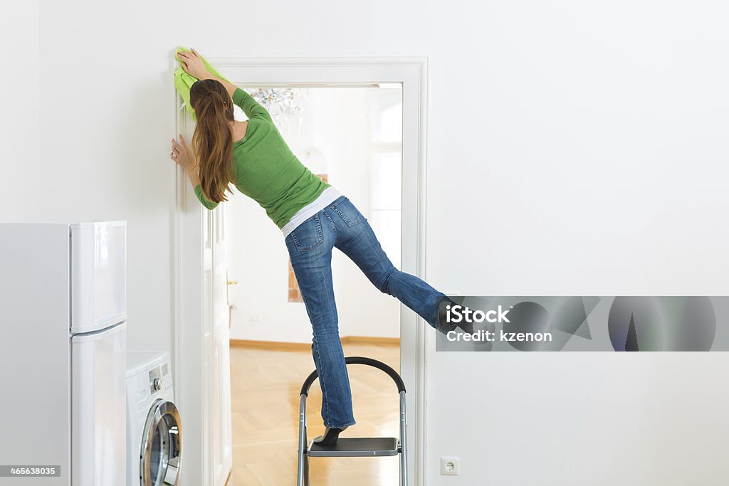 Woman at the spring cleaning working dangerously Young woman cleaning at home, she has a cleaning day and using a duster or dust cloth Misfortune Stock Photo