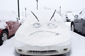 Sad face emoticon drawn on snow on a car
