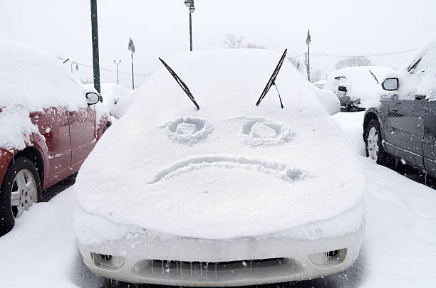 Sad face emoticon drawn on snow on a car stock photo