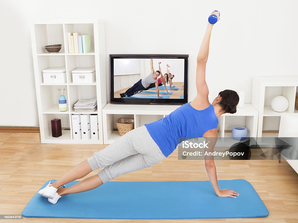 Mujer ejercicio en una estera de yoga en frente del televisor - Foto de stock de Televisión libre de derechos