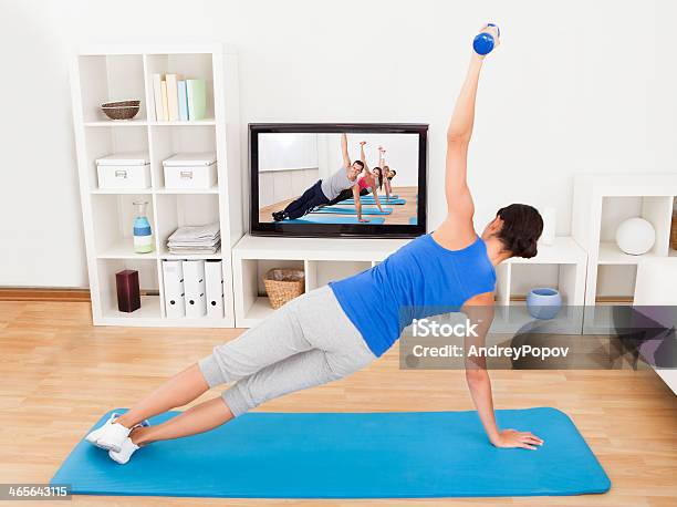 Mujer Ejercicio En Una Estera De Yoga En Frente Del Televisor Foto de stock y más banco de imágenes de Televisión