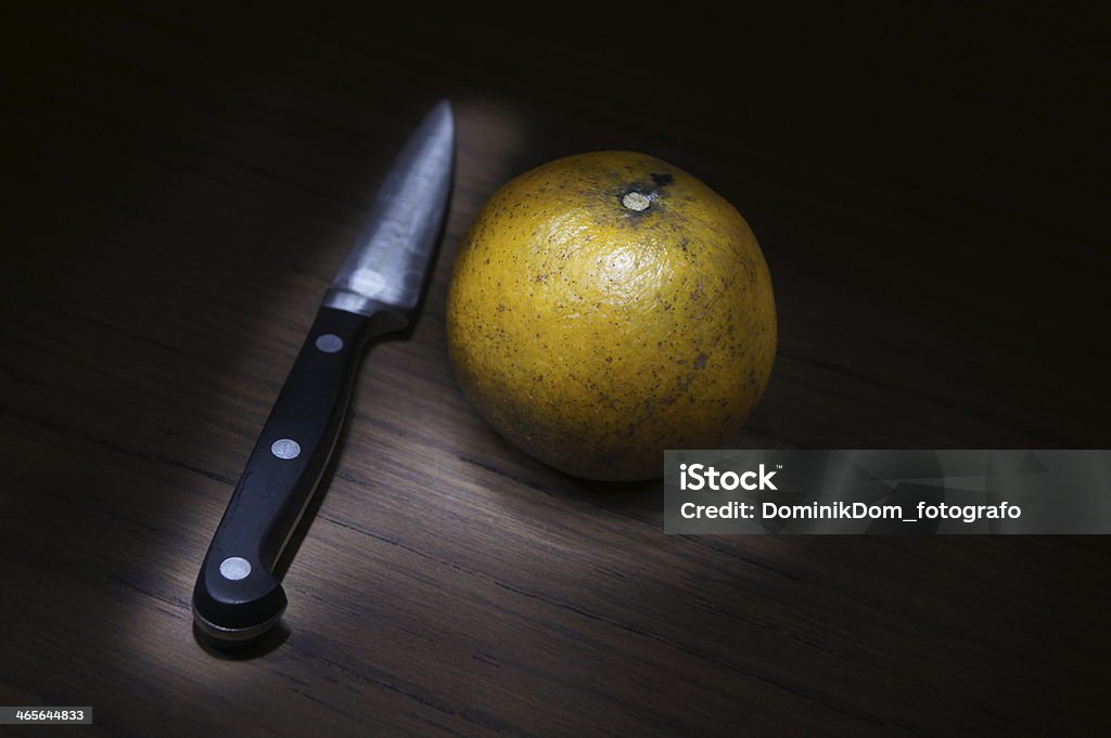 Last Orange with a knife it´s the last orange in table and there is a knife with it so somebody have to cut it up Domestic Kitchen Stock Photo