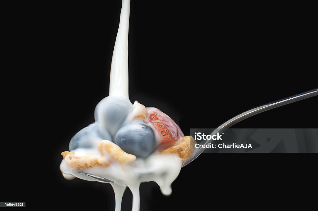 Breakfast spoon Milk pouring over a spoon with berries and cereal over a black background Berry Fruit Stock Photo