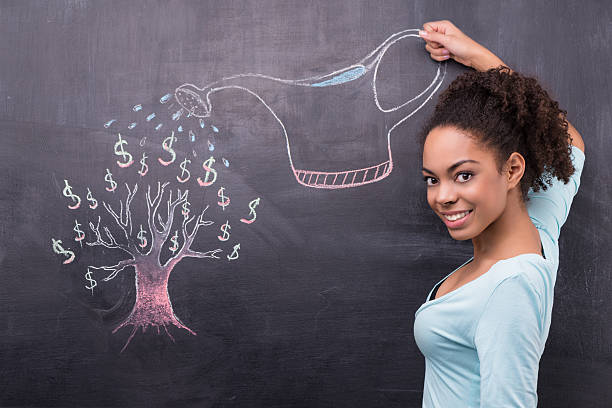 Young afro-american woman watering dollar tree painted on chalkboard