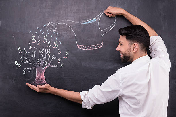istock Businessman watering dollar tree painted on chalkboard 465649794