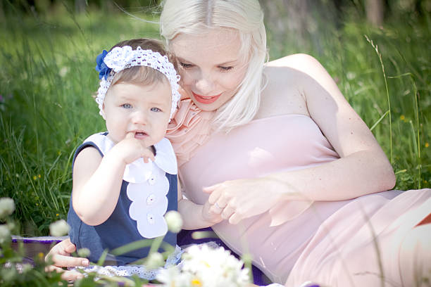 istock mother and daughter are sitting in the grass 465656363