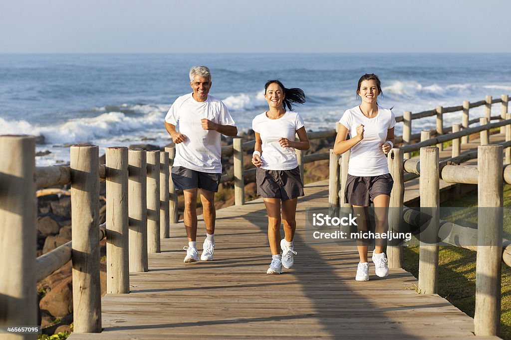 fit family jogging at the beach cheerful fit family jogging at the beach in the morning Adult Stock Photo