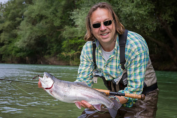 istock Flyfisherman holding a rainbow trout 465668551