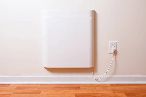 A wall-mounted electric convection heater in a house room. This particular installation acts as supplemental heat when temperatures get very cold outside. This heater is very energy efficient, air is drawn up from the bottom and rises across a heating panel out the top without the use of a fan.