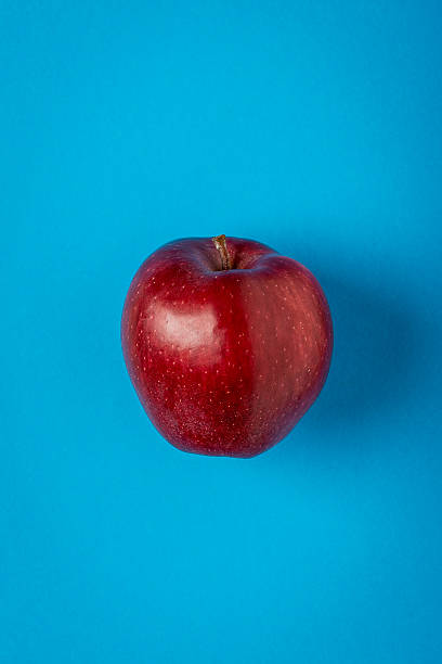 istock Red apple on blue paper background, minimalist still life 465675878