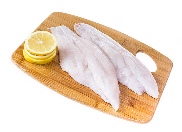 Fresh Catfish Fillets Fresh catfish fillets on a cutting board with lemon and isolated on white. fillet stock pictures, royalty-free photos & images