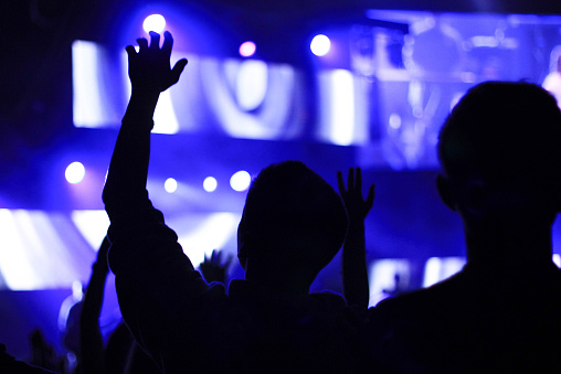 Photo taken from behind of a boy with his hand up in worship.