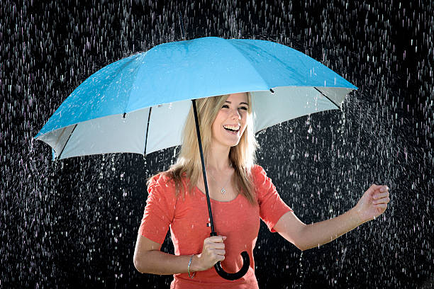 istock Laughing Young woman with blue umbrella enjoying rain 465680453
