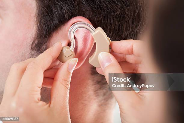 Woman Adjusting A Hearing Aid On A Man Stock Photo - Download Image Now - Hearing Aid, Part Of, Deafness