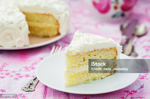 Slice Of Yellow Cake With White Frosting On Pink Table Stock Photo - Download Image Now