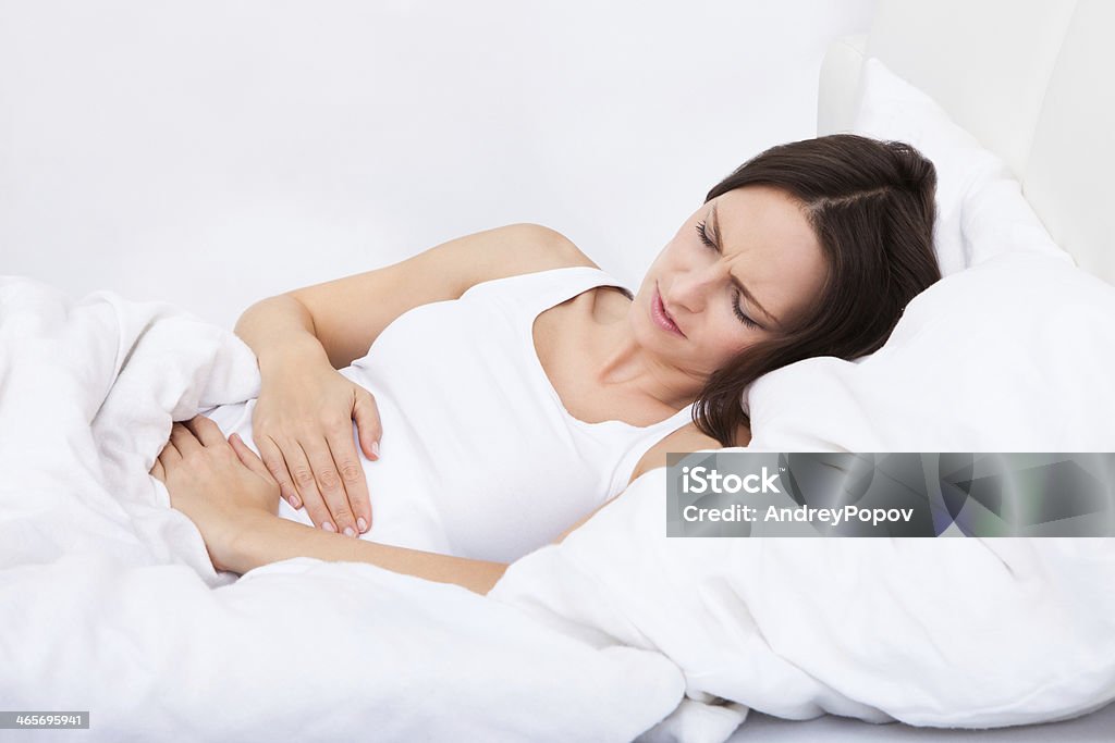 Woman with stomach ache lying on bed Portrait of woman with stomach ache lying on bed Abdomen Stock Photo