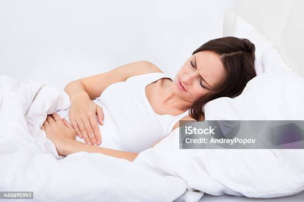 Woman With Stomach Ache Lying On Bed Stock Photo - Download Image Now - Abdomen, Adult, Beautiful People