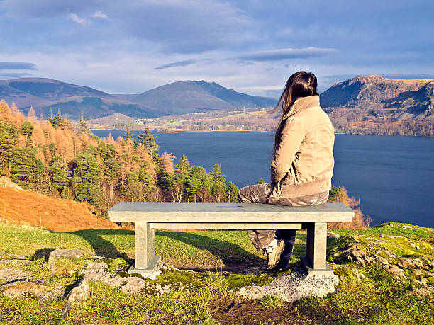 Bench with woman. View at Derwent Water, Cumbria, UK.View at Derwent Water, Cumbria, UK. derwent water stock pictures, royalty-free photos & images