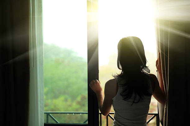 istock girl opening curtains in a bedroom 465703408