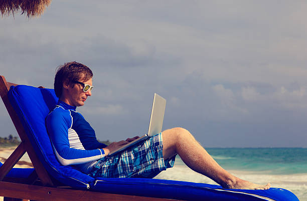 istock man with laptop on beach vacation 465703440