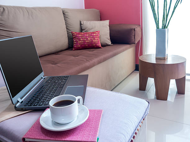 Modern, beige living room with open laptop and coffee cup