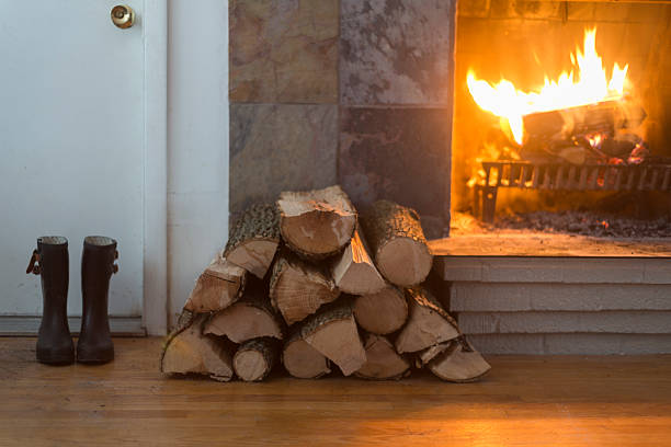 Fireplace Slate titled fireplace with wood stack and boots by the door. firewood photos stock pictures, royalty-free photos & images