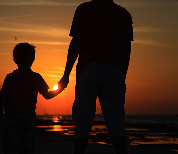 istock father and son holding hands at sunset 465721922