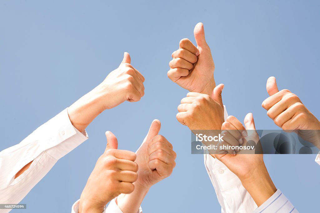 Thumbs up Image of several human hands showing thumbs up against clear blue sky 2015 Stock Photo
