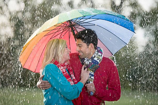 istock Young couple under multi colored umbrella enjoying rain 465735437