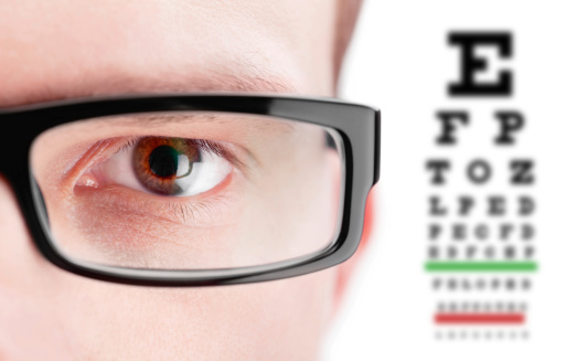 This is a photo of black reading glasses sitting on top of a small eye chart. The background is a pure white and there is a clipping path included with this file.