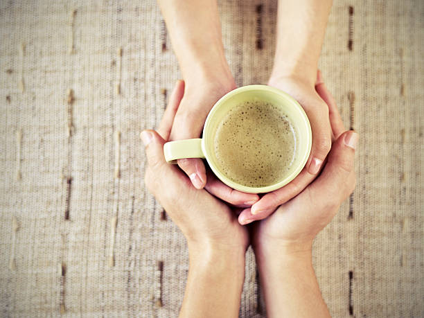 istock Man and woman's hands holding a cup of coffee together 465750372