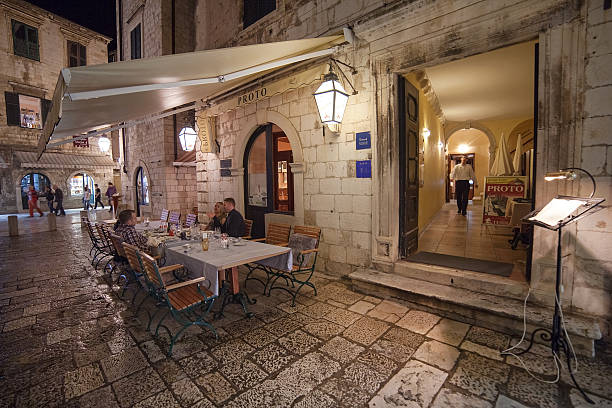 Dubrovnik, Croatia - May 27, 2014: People sitting at the table at restaurant Proto's  terrace. Dubrovnik has many restaurants which offer traditional Dalmatian cuisine and some great wine lists.