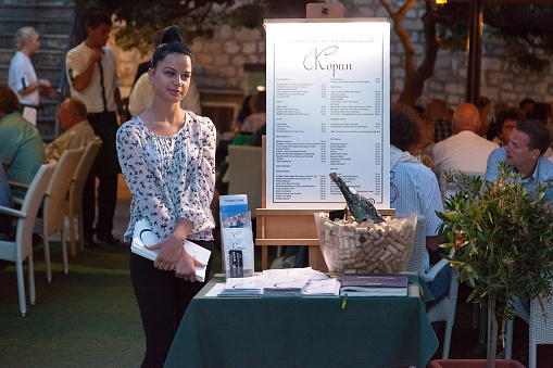 Dubrovnik, Croatia - May 28, 2014: Restaurant Kopun's hostess standing in front of the entrance. Dubrovnik has many restaurants which offer traditional Dalmatian cuisine and some great wine lists.