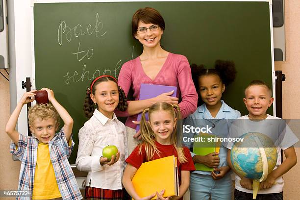 Teacher With Her Students In Front Of A Blackboard Stock Photo - Download Image Now - 2015, Adult, Boys
