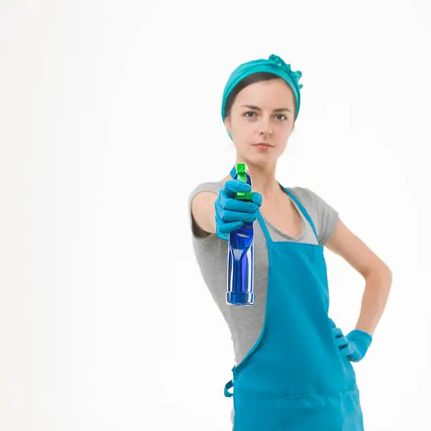 portrait of cleaning woman aiming spray bottle in front of her, on white background