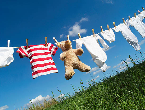 Baby clothing on a clothesline Baby Clothing and a teddybear on a clothesline towards blue sky teddy bear hanging stock pictures, royalty-free photos & images