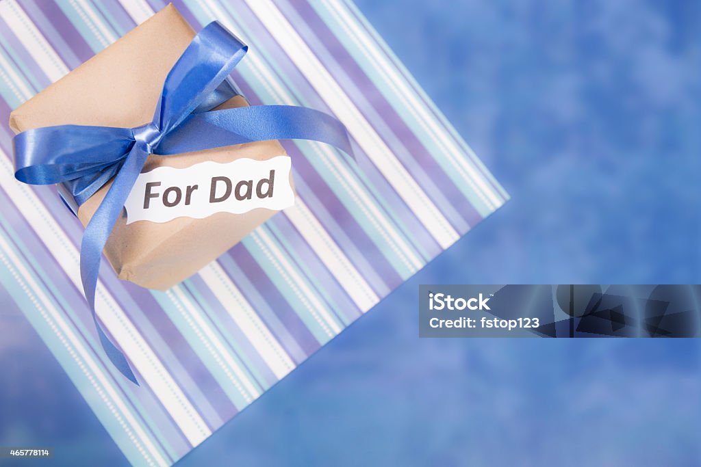 Happy Father's Day.  Gift for dad on blue, striped background. Holidays. Father's Day gift box for dad on blue background. Blue bow on brown box. Striped background. 2015 Stock Photo