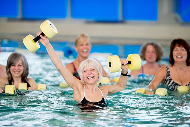 senioren wasser-aerobic - gym yellow muscular build dumbbell stock-fotos und bilder