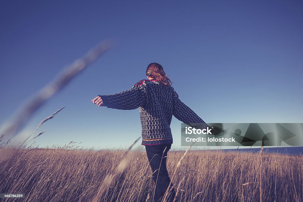 Young woman spinning around in meadow by the sea Young woman is spinning around in a meadow by the sea Adult Stock Photo