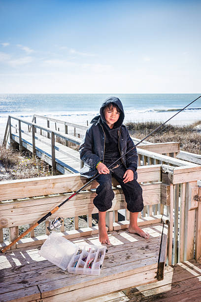 Adorable little boy at white sand beach fishing