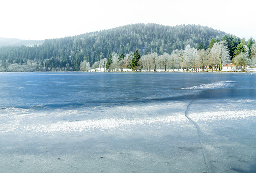 Landscape of frozen Longemer lake in the Vosges Mountain, France