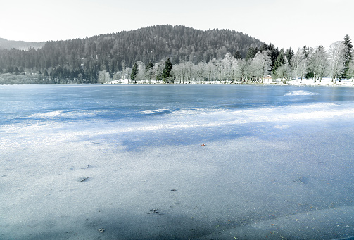 Landscape of frozen Longemer lake in the Vosges Mountain, France