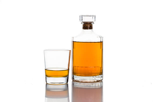 A glass of whiskey on neat with bottle in white background