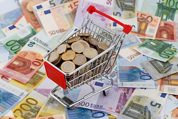Shopping Trolley with Money A shopping trolley full of one euro, two euro and fifty cent coins and placed on a lot of five, ten, twenty, fifty, one hundred, two hundred and five hundred euro banknotes scattered around all over the floor. five euro banknote photos stock pictures, royalty-free photos & images
