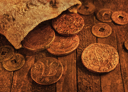 Close up of old ancient coins on wooden background in candle light, with grunge texture effect. Source file of texture included
