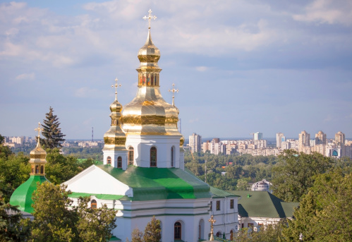 Gilded cupolas  of Caves Monastery in Kiev against modern buildings of the city.