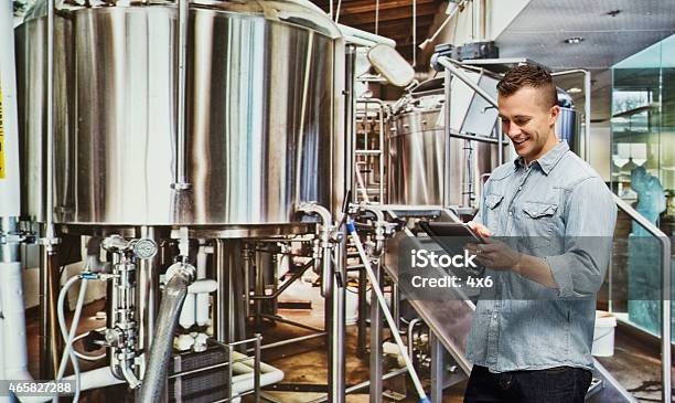 Smiling Brewmaster Working With Tablet Stock Photo - Download Image Now - Digital Tablet, Brewery, Holding