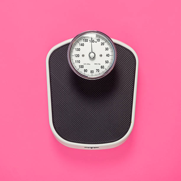 Black weighing scales on pink background