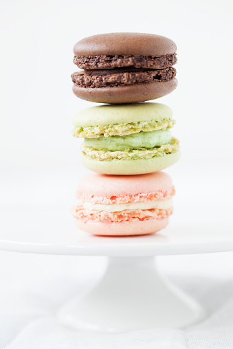 Three french macaroons stacked on a white cake plate.